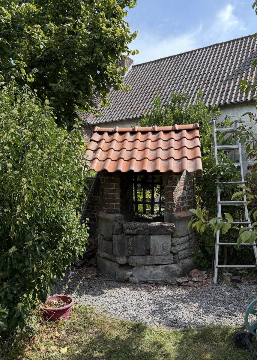 Puits en pierres restauré — couverture tuiles rouges neuves